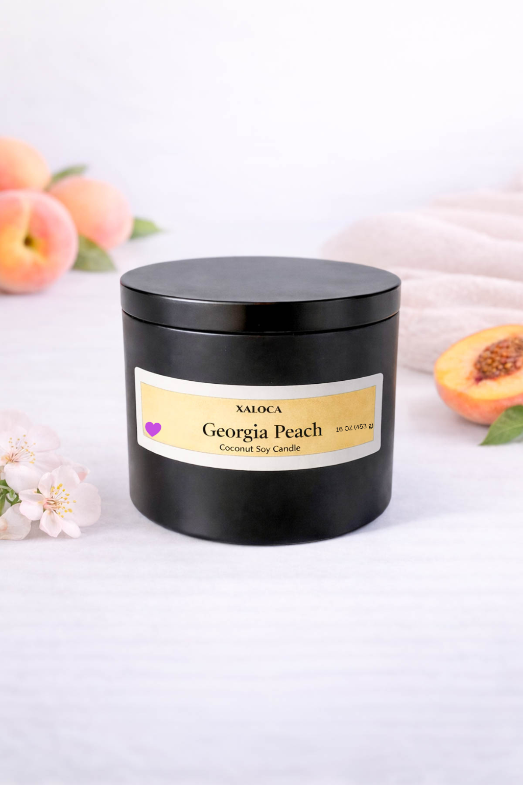 Black candle jar with 'Georgia Peach' label on a white background with peaches and flowers.