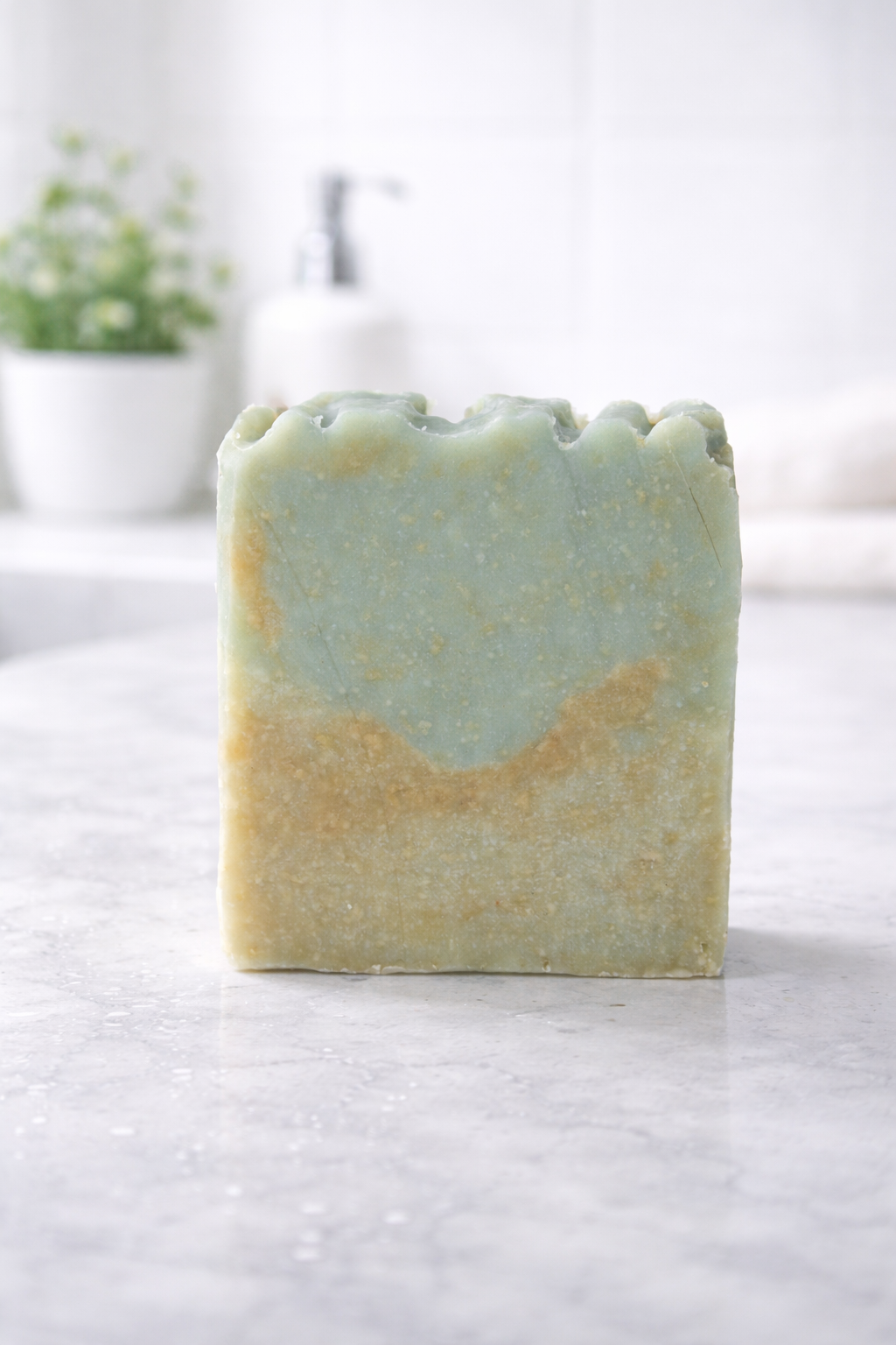 Handmade soap bar with a gradient of green and yellow on a white surface.