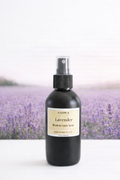 Black spray bottle labeled 'Lavender' with a lavender field in the background