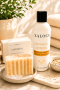 Xaloca Oatmeal Lotion bottle displayed with a boxed product, a bar of oatmeal soap, and spa props including folded towels and a plant in a warm, natural setting.