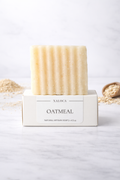 Bar of oatmeal soap in a white box on a light background