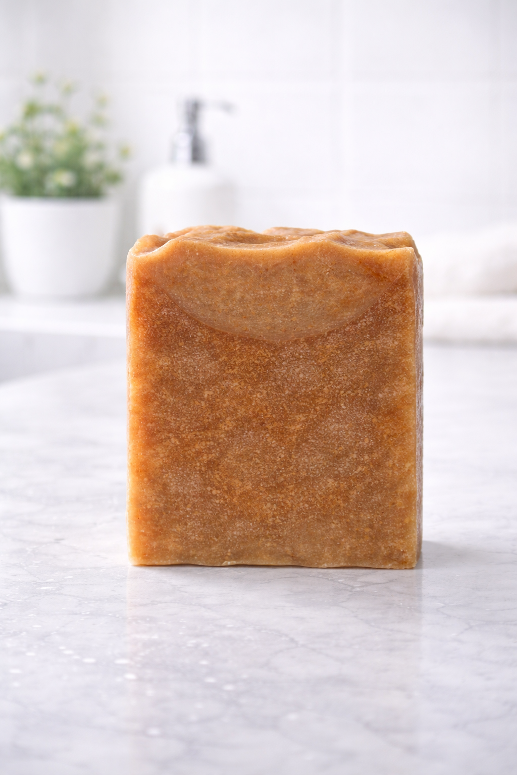 Bar of brown soap on a white marble surface with a blurred background